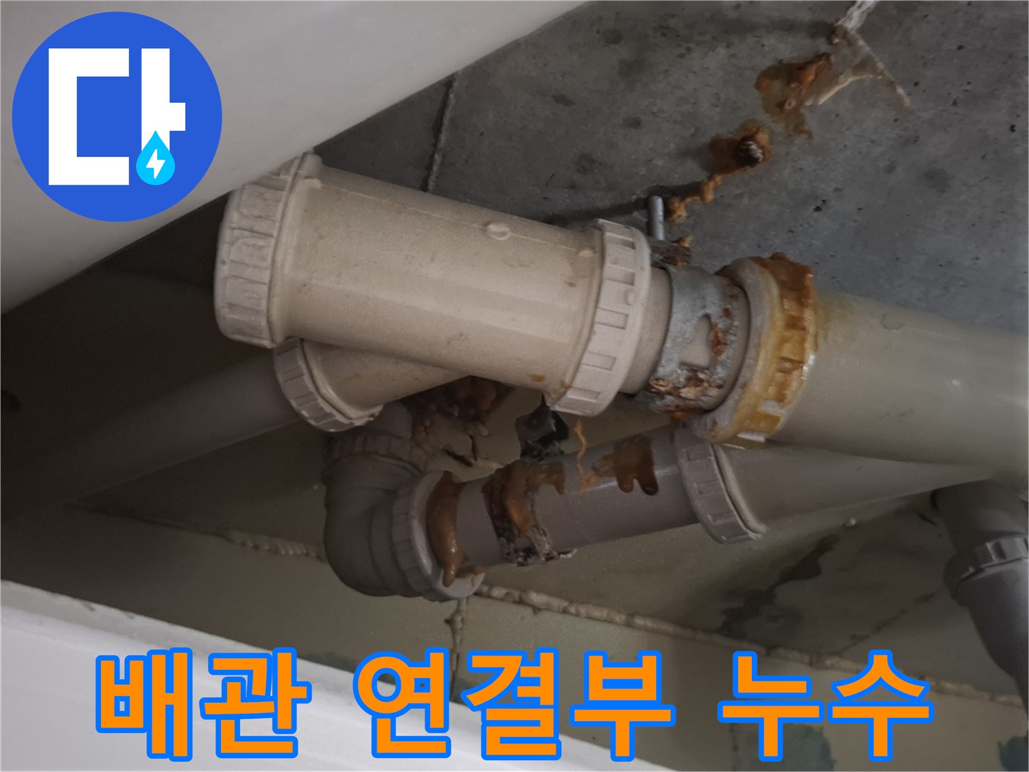 배관 연결부 누수 - 배관 연결 부위에서 물이 새어 나와 고여 있는 모습입니다.