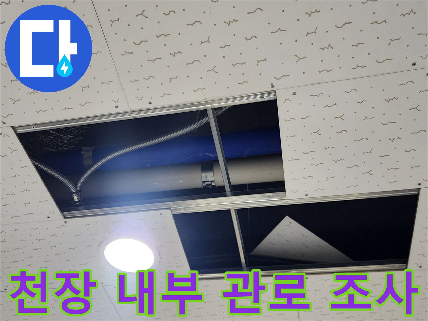천장 텍스 판넬 사이로 보이는 은색 주름관과 파란색 배관의 모습