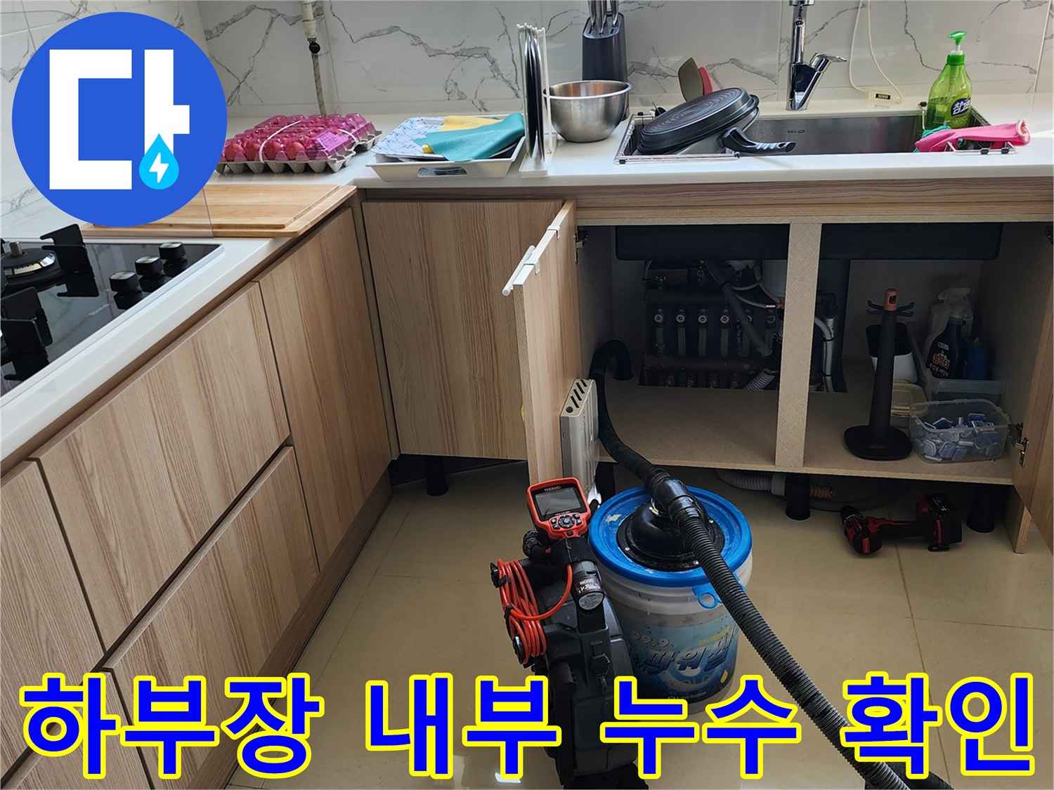 싱크대 하단 배관 주변의 물기를 제거하며 누수 부위를 찾는 작업 장면입니다.