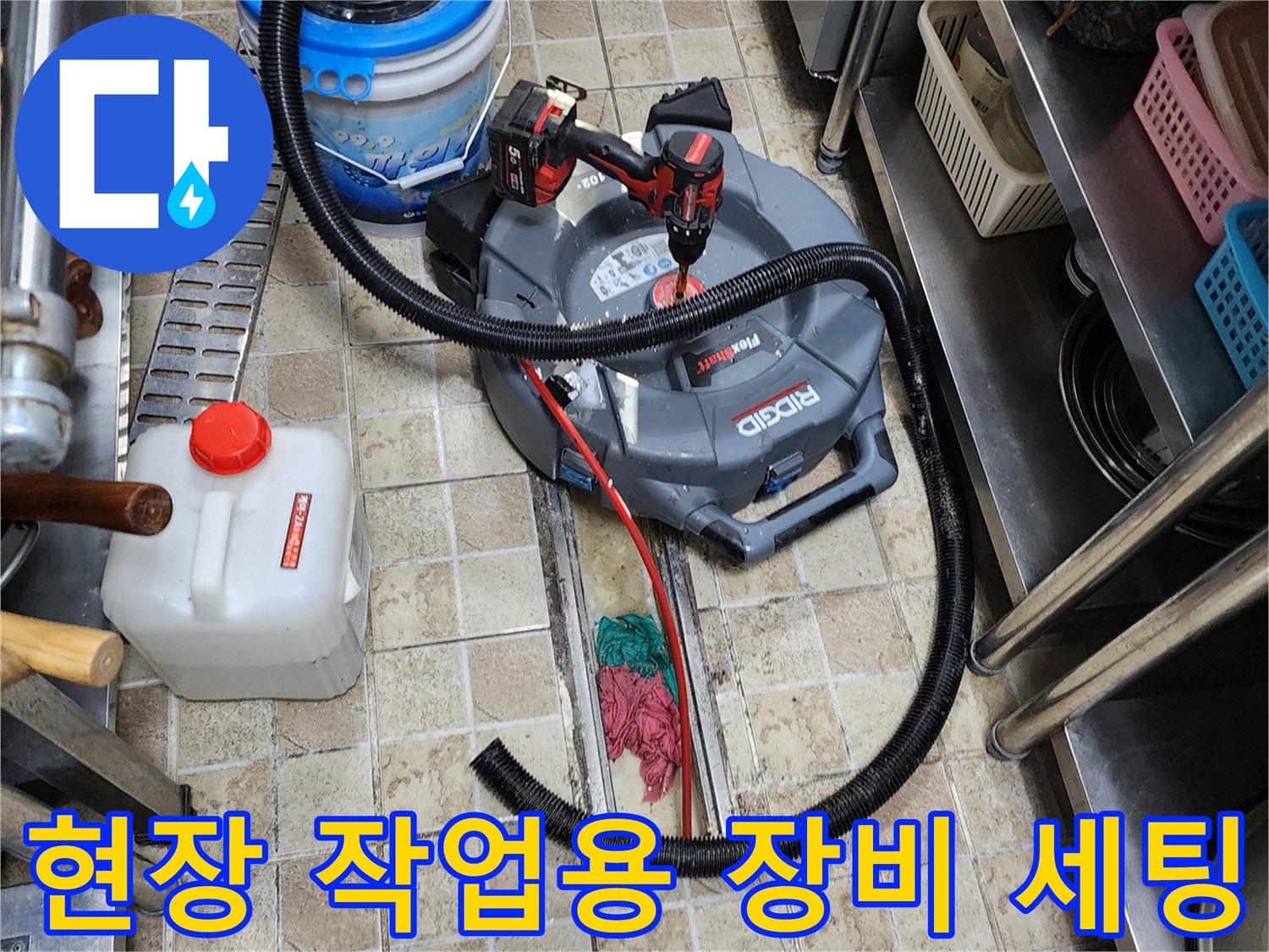 바닥 타일 위에 놓인 산업용 청소기와 전동 드릴 기구