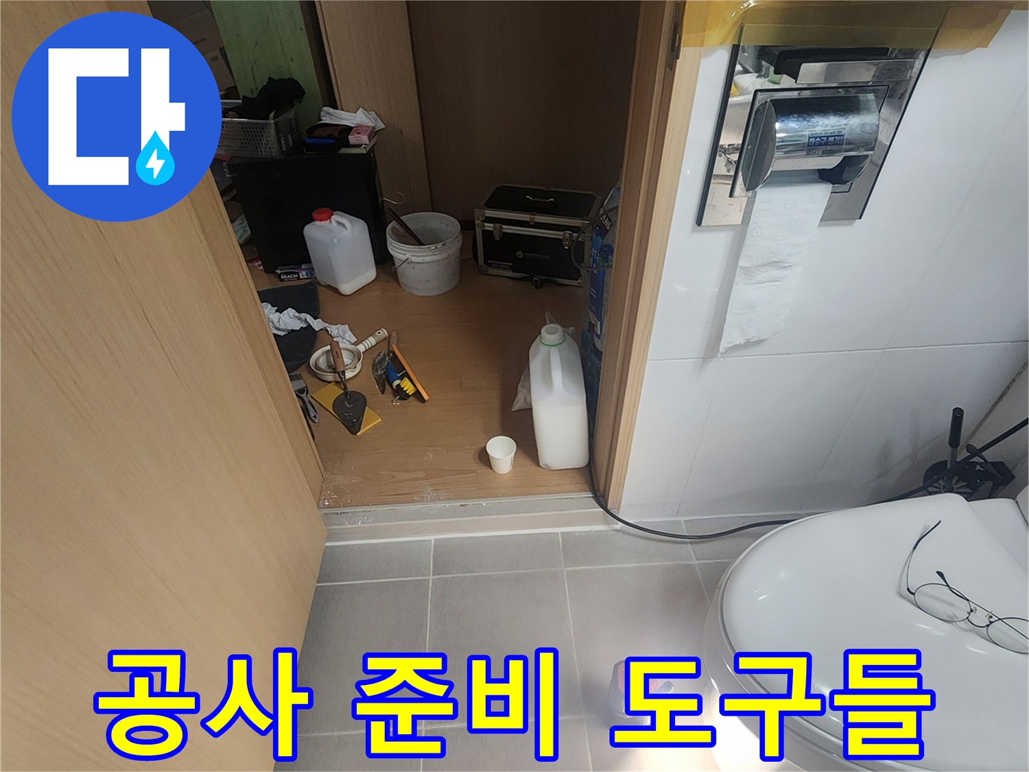 화장실 바닥에 놓인 청소 용품과 공사 장비 세트