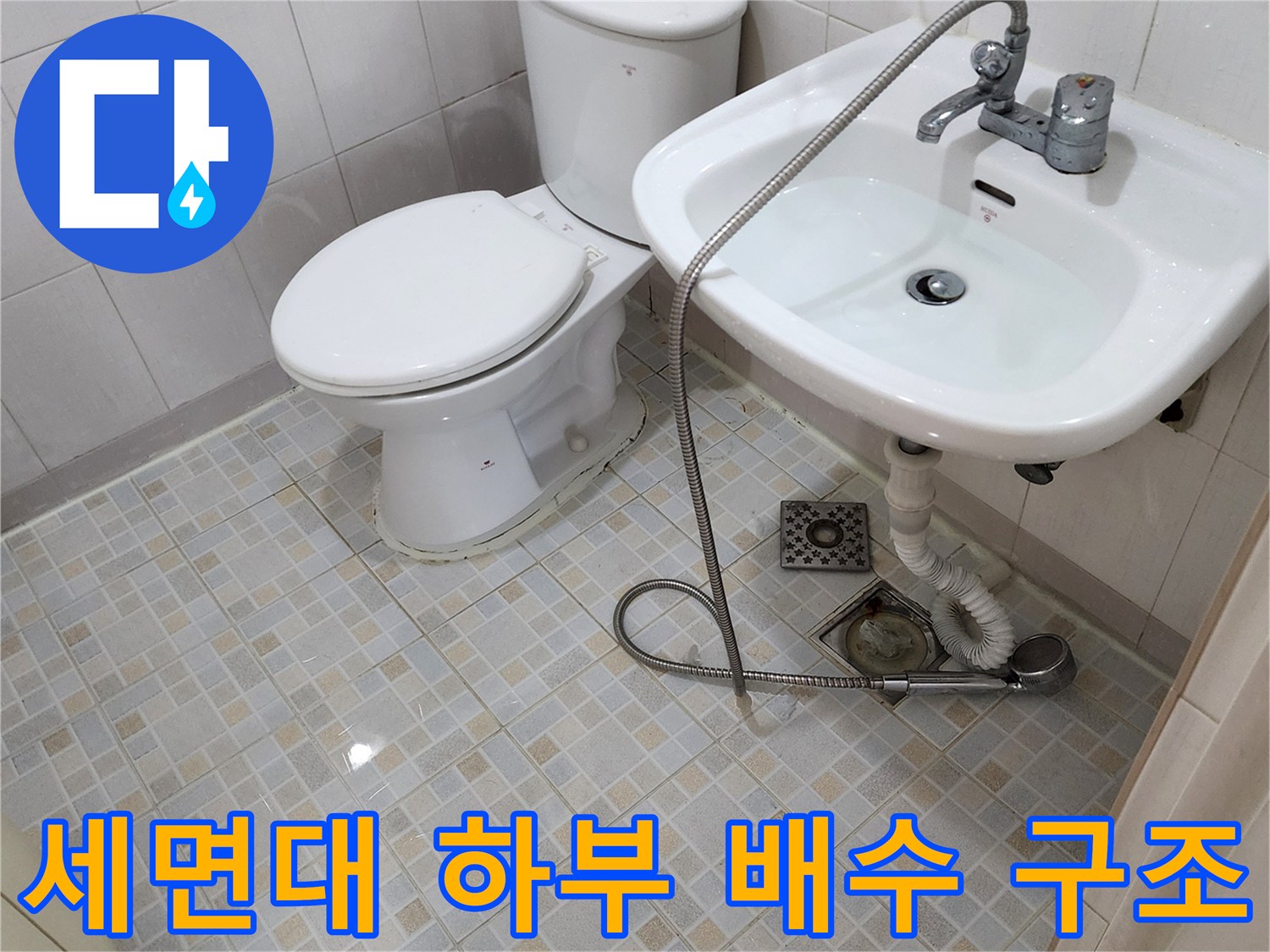 세면대 수전 아래쪽 급수 호스와 바닥 배수구 모습입니다.