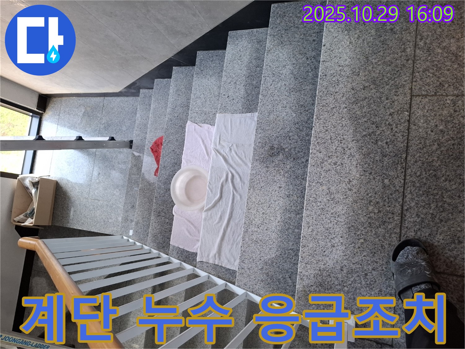 계단에 놓인 대야와 수건 - 긴급 누수 상황에 대한 임시 조치입니다.