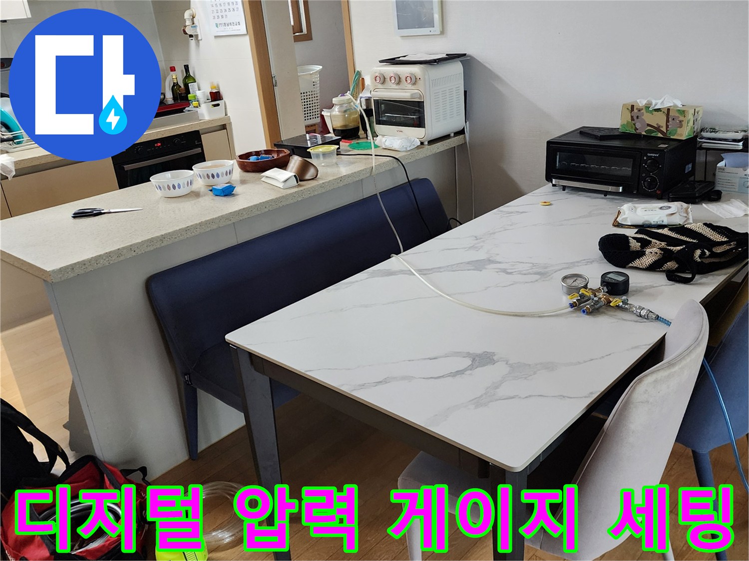 식탁 위에 놓인 디지털 압력계와 작업용 배관 부품들