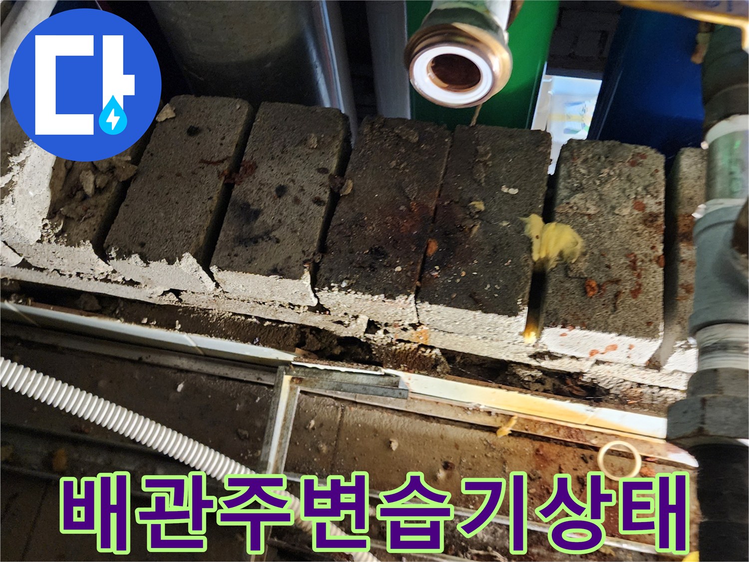 축축하게 젖은 벽돌과 노출된 금속 부속 배관