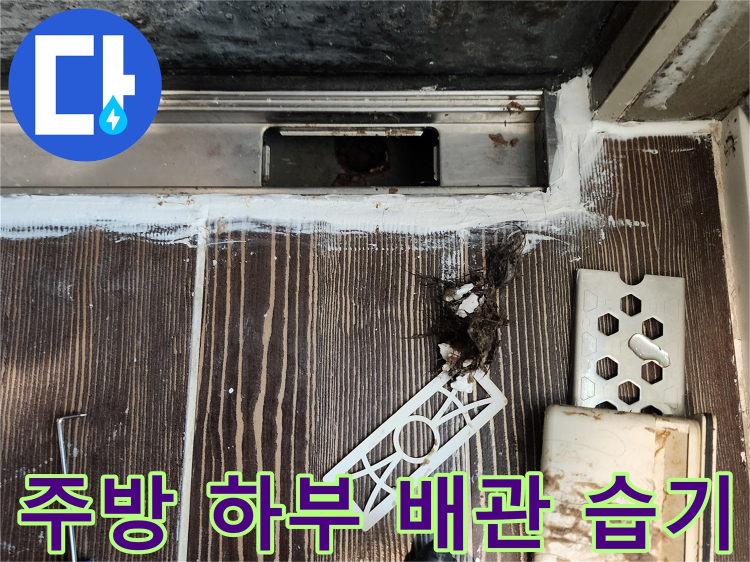 싱크대 밑 배관 주변의 젖은 흔적과 오염된 잔해물 모습