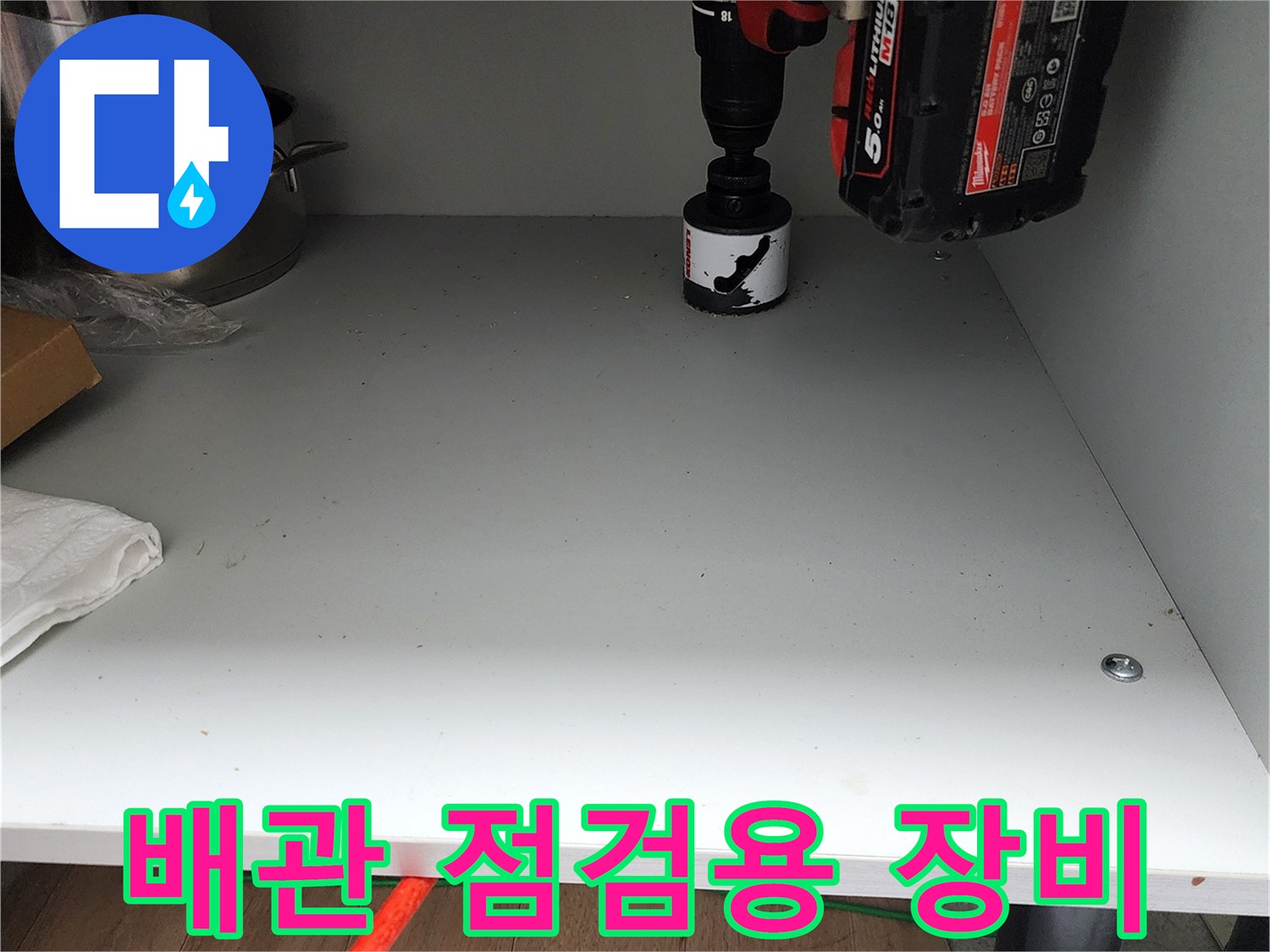 싱크대 밑바닥에 놓인 전동 드릴과 작업 도구들