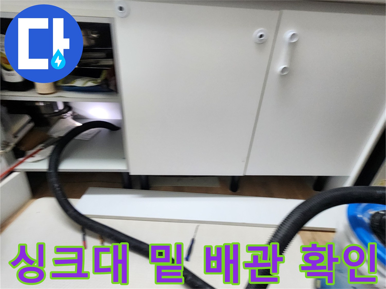 싱크대 하부장 내부의 배관과 주변 바닥 공간을 점검 중인 장면