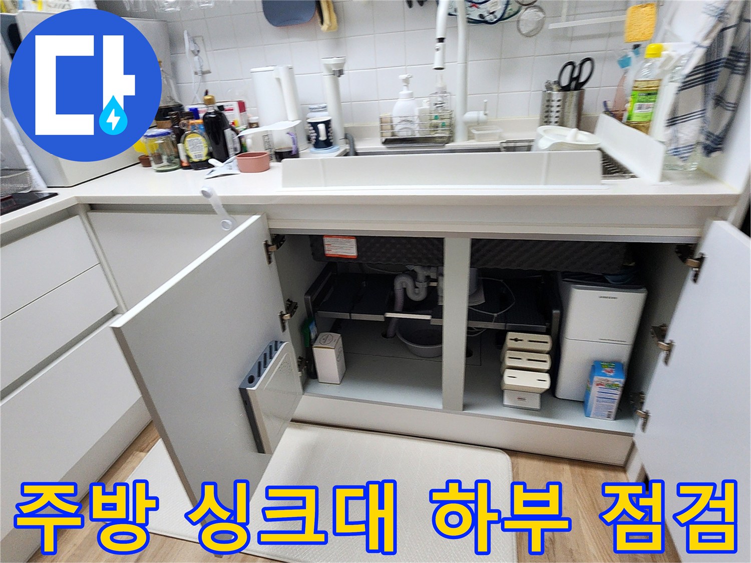 열려 있는 싱크대 하부장 내부의 배관 및 주변 환경 촬영