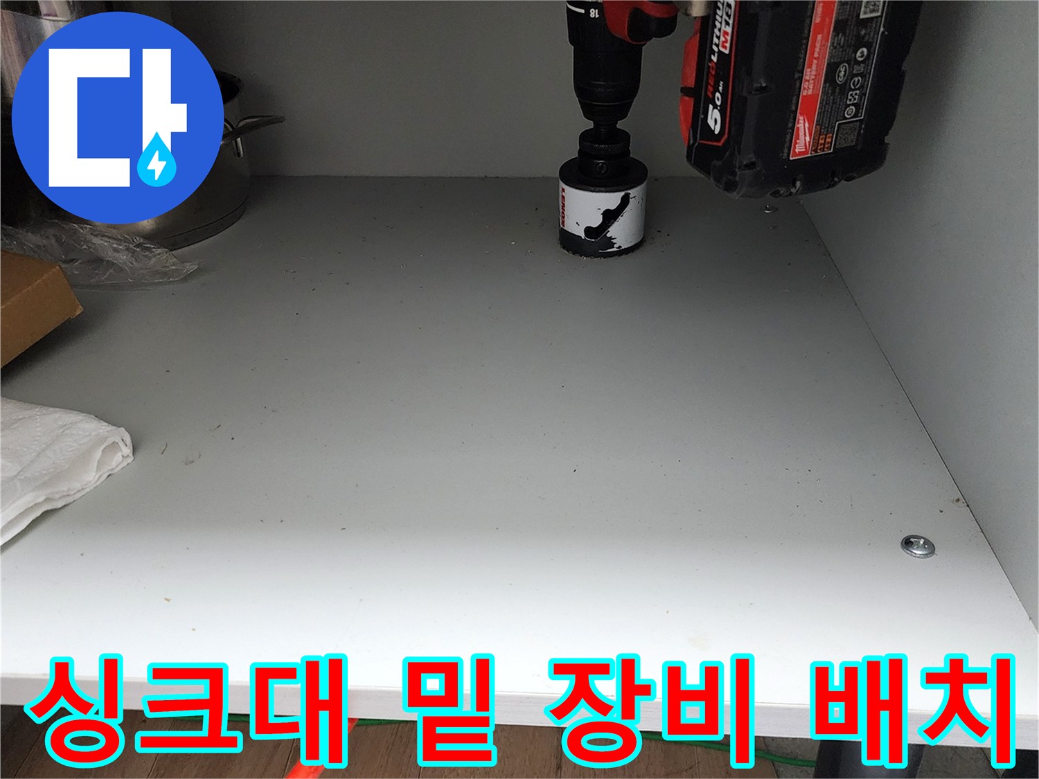 작업을 위해 하부장 바닥에 놓여 있는 전동 드릴과 용기들