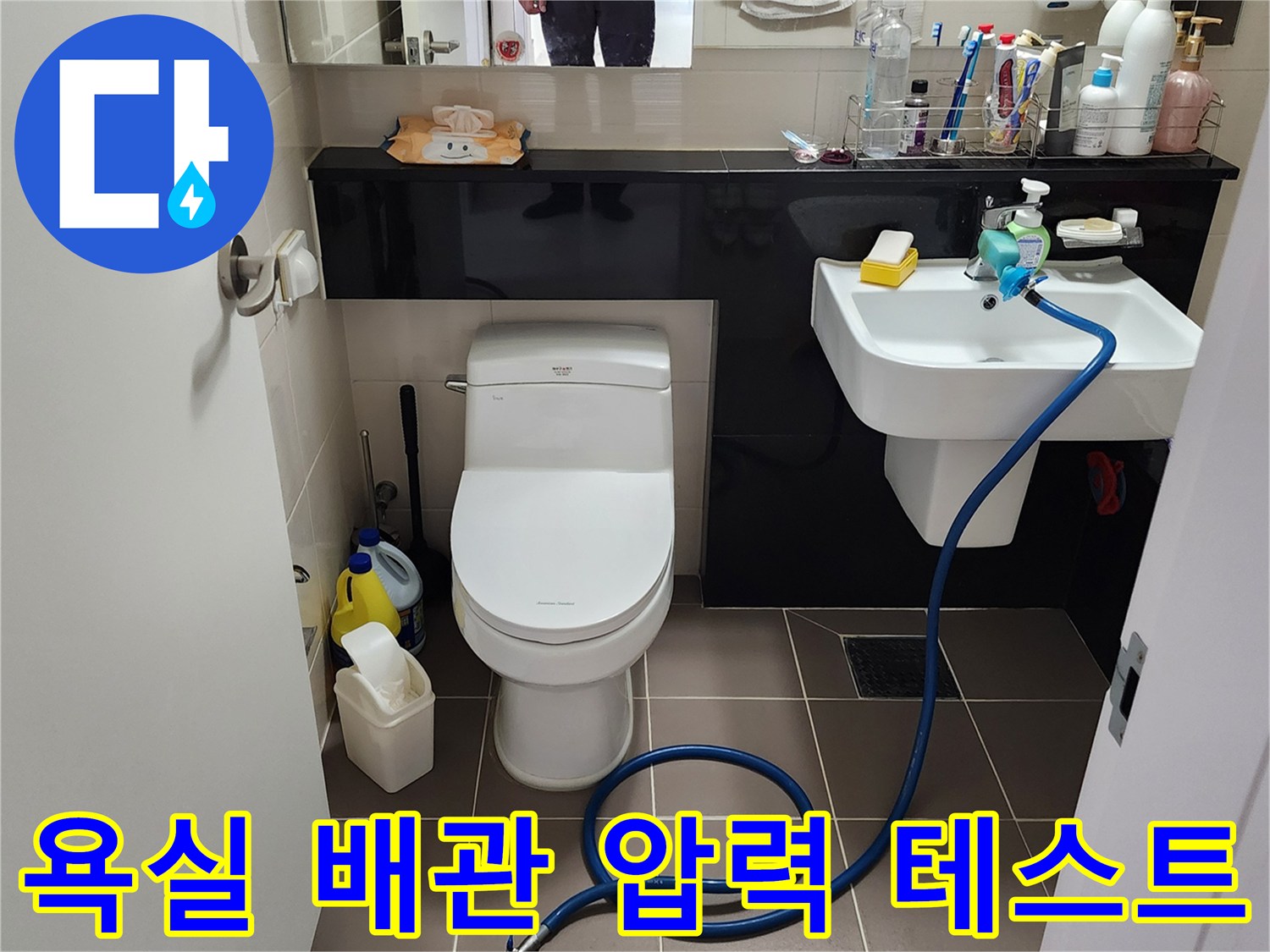 세면대 하부 수전 부위와 바닥에 놓인 점검용 호스