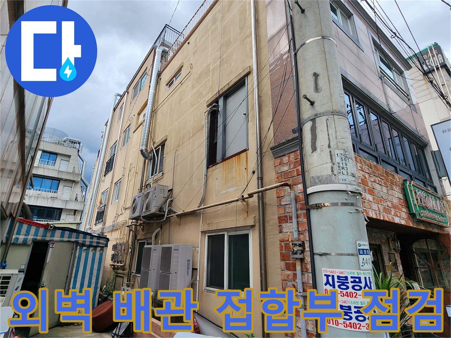 건물 외벽의 노출된 배관과 벽체 하단부 상태를 보여주는 사진