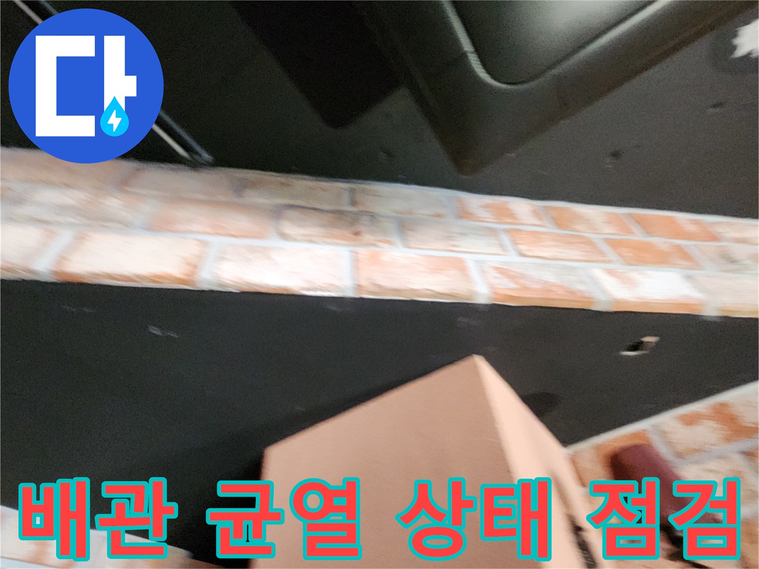 벽돌 벽면 사이로 노출된 배관의 파손 부위 근접 촬영