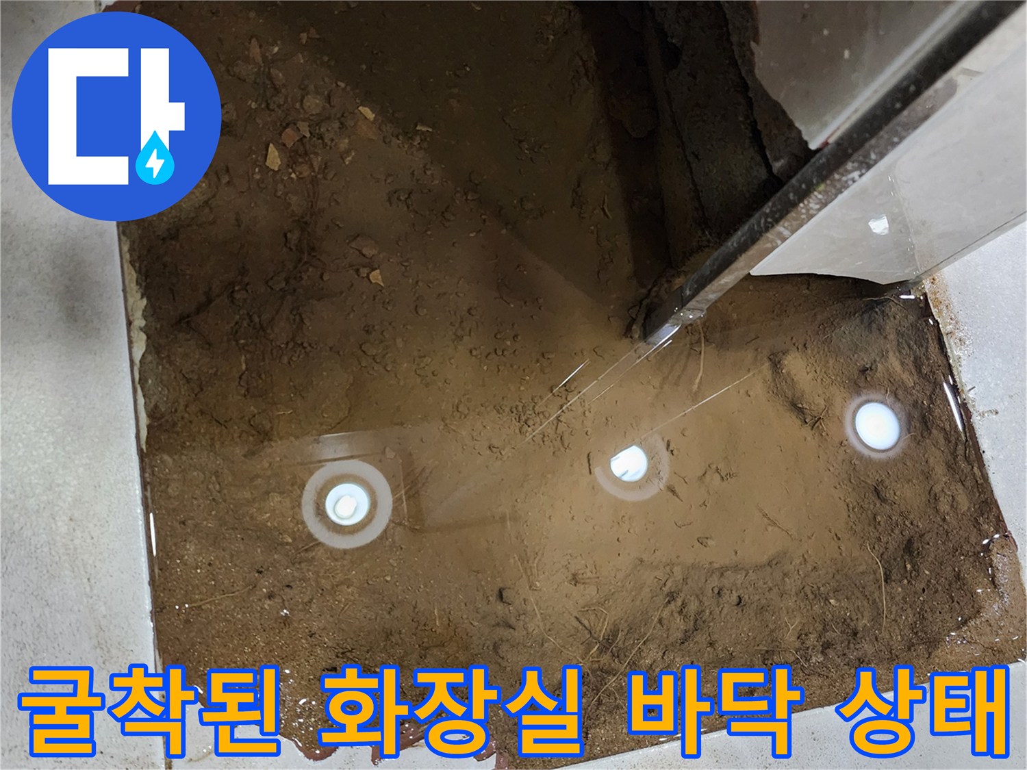 화장실 타일 제거 후 드러난 배관 주변의 젖은 지반 사진
