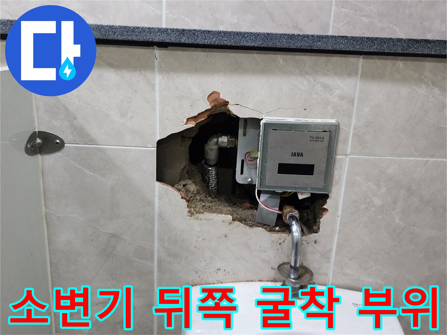 훼손된 타일 사이로 노출된 소변기용 자동 세척 밸브와 배관 연결 상태