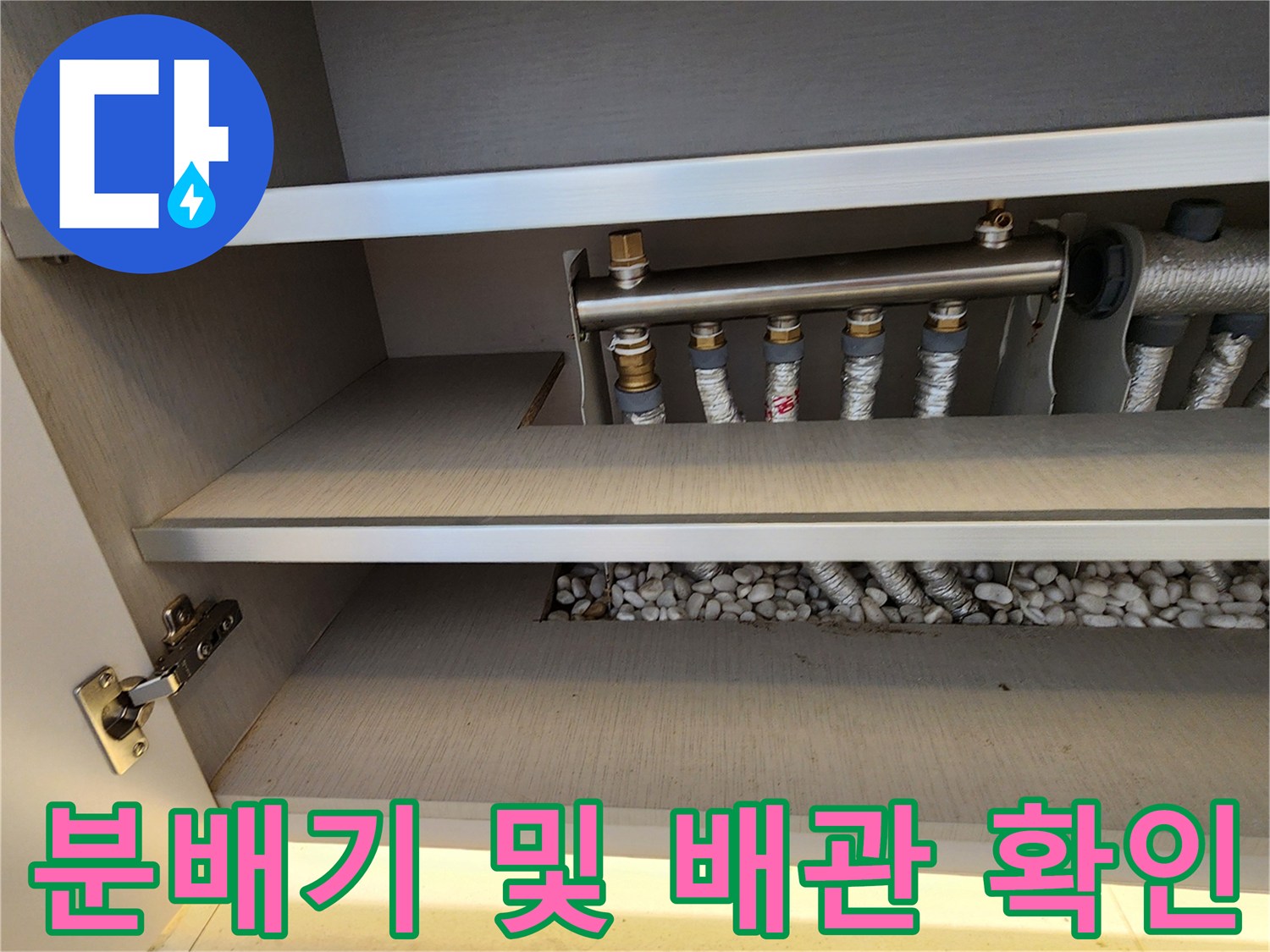 금속 분배기와 보온재가 입혀진 배관이 있는 하부장 내부입니다.