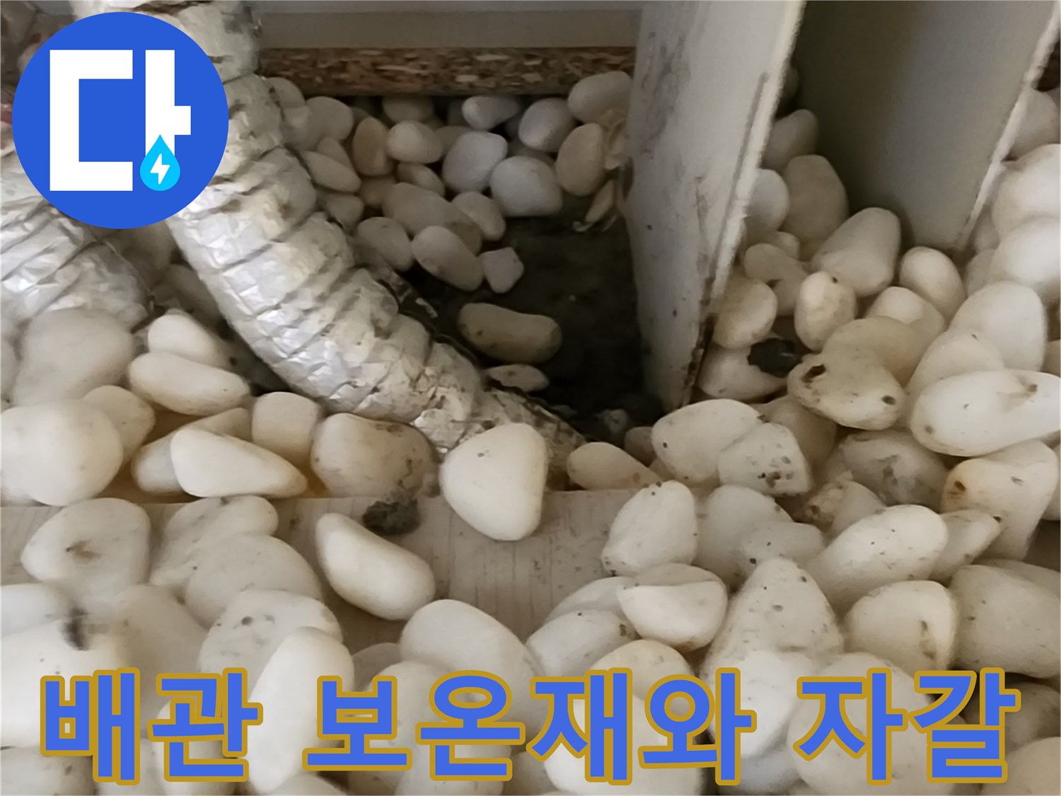 배관의 보온재와 주변에 깔린 자갈층을 보여주는 상세 사진입니다.