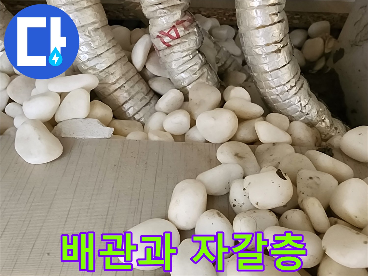 보온재로 감싸진 배관-주변에 깔린 하얀 자갈
