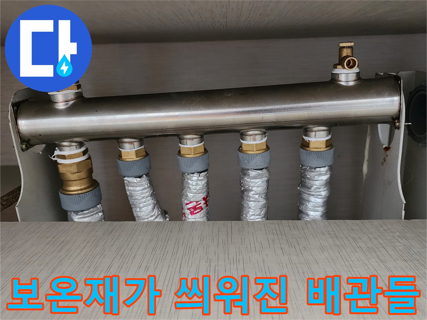 은색 보온재로 마감된 난방 배관-분배기 하부 연결 부위 상세