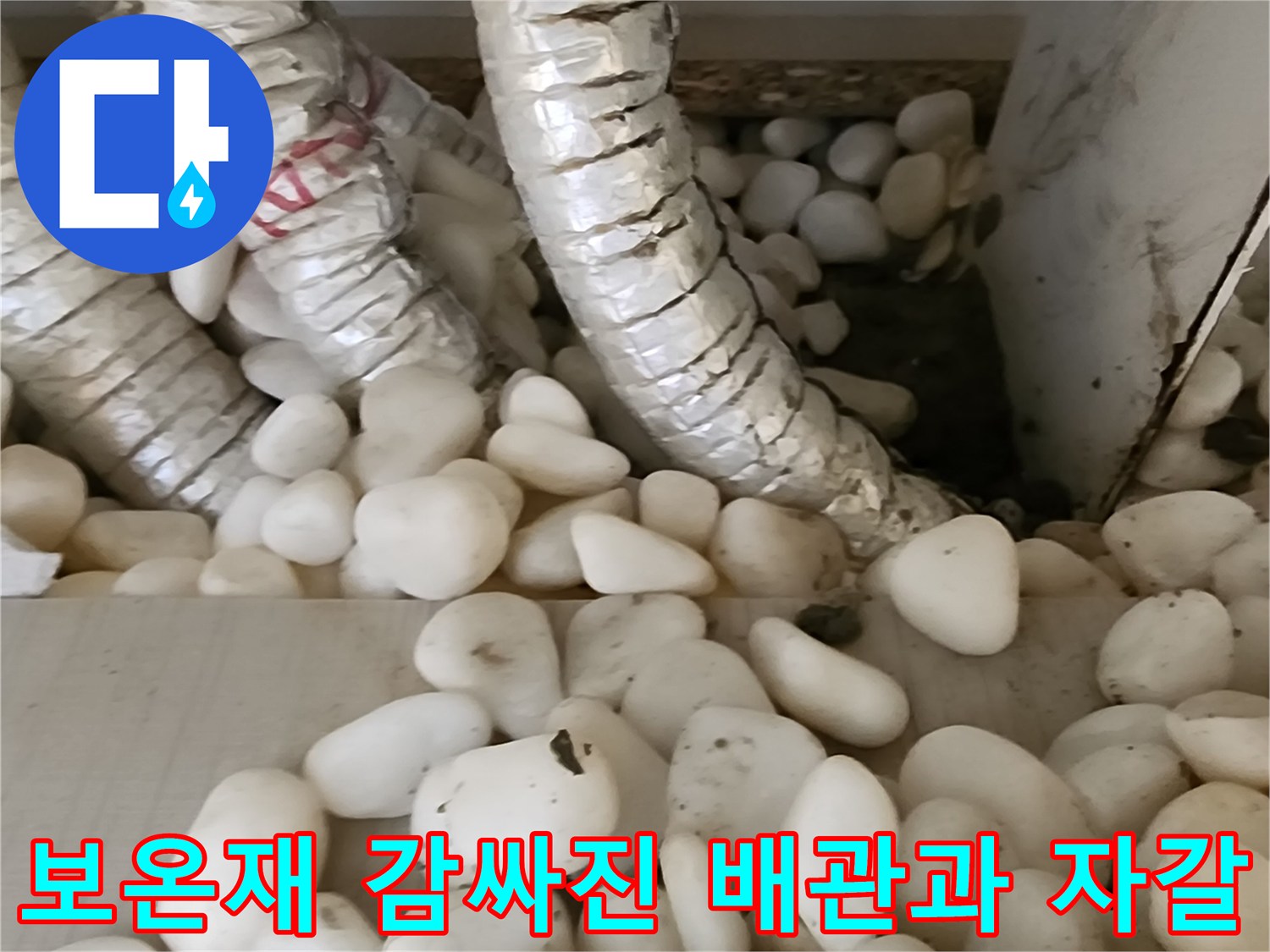 은색 보온재로 마감된 배관과 하단 자갈층 모습