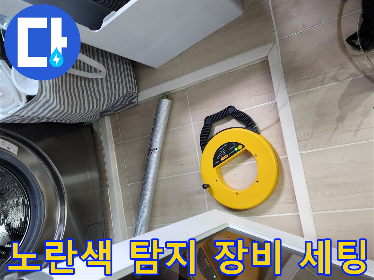 세탁실 바닥 타일 위에 놓인 노란색 배관 검사 장비