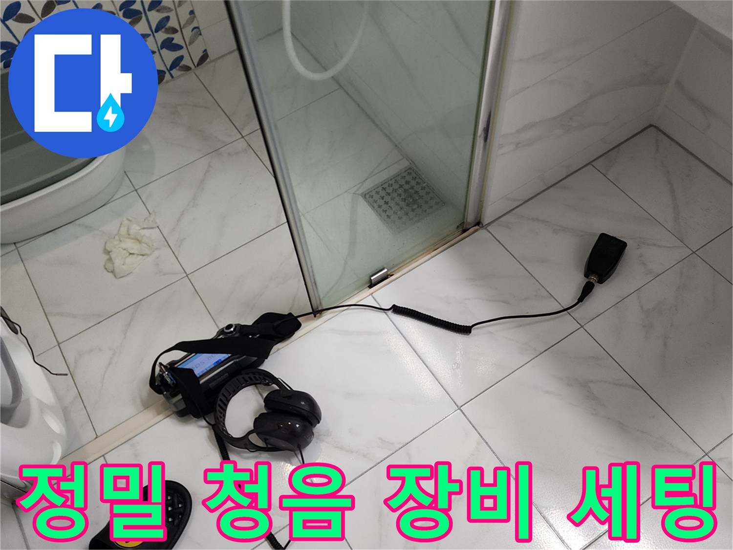 욕실 타일 위 디지털 누수 탐지기와 헤드셋의 모습