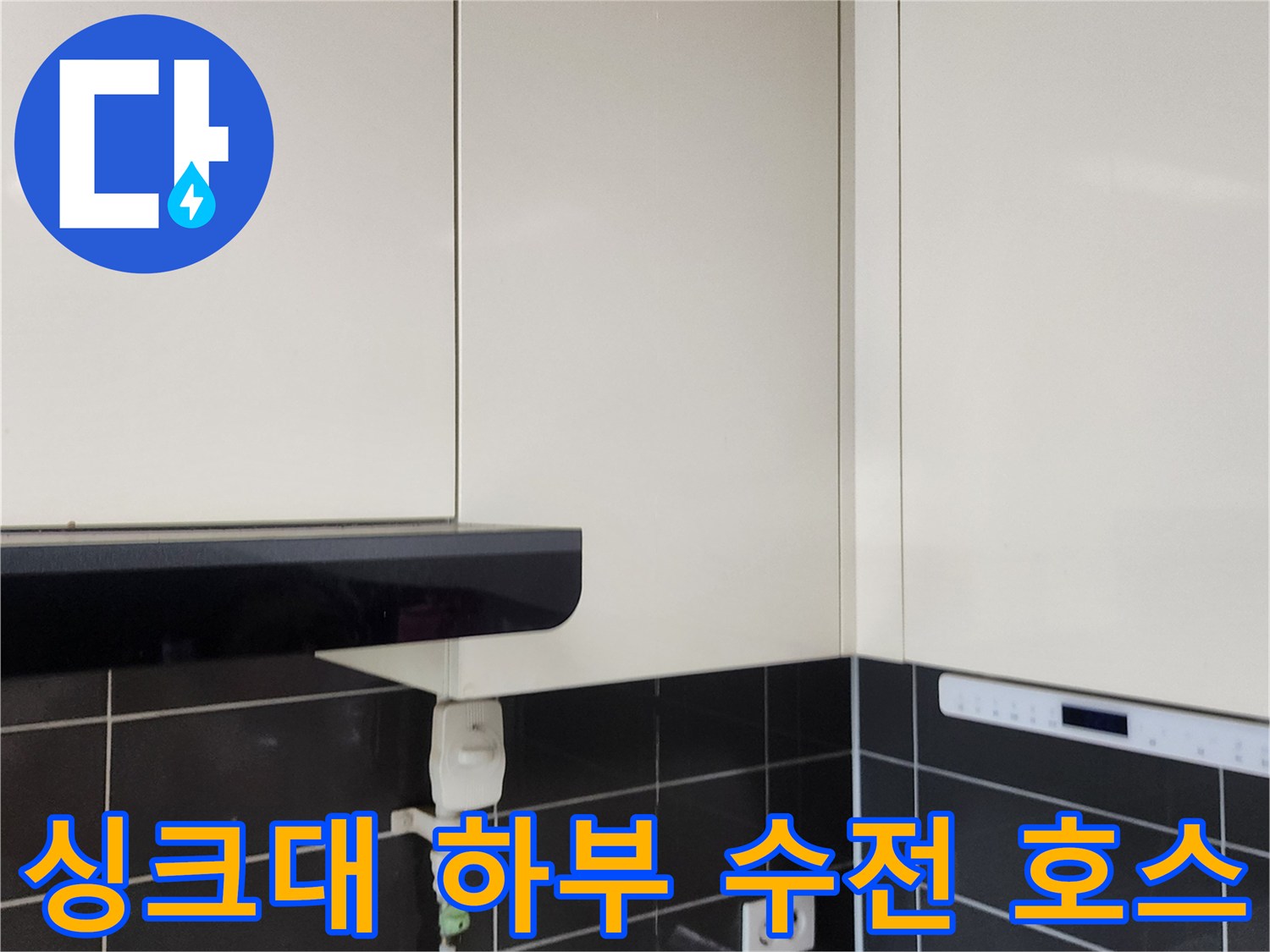 주방 싱크대 아래쪽 배관 연결 부위와 콘센트 근접 사진
