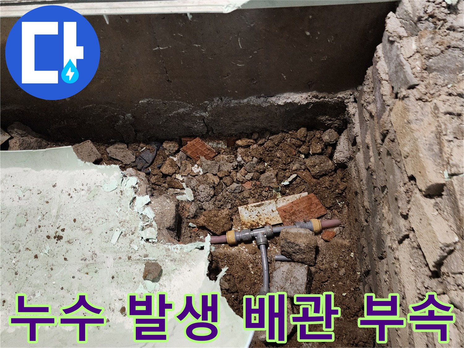 흙과 잔해물 사이로 드러난 누수가 진행 중인 T자 배관