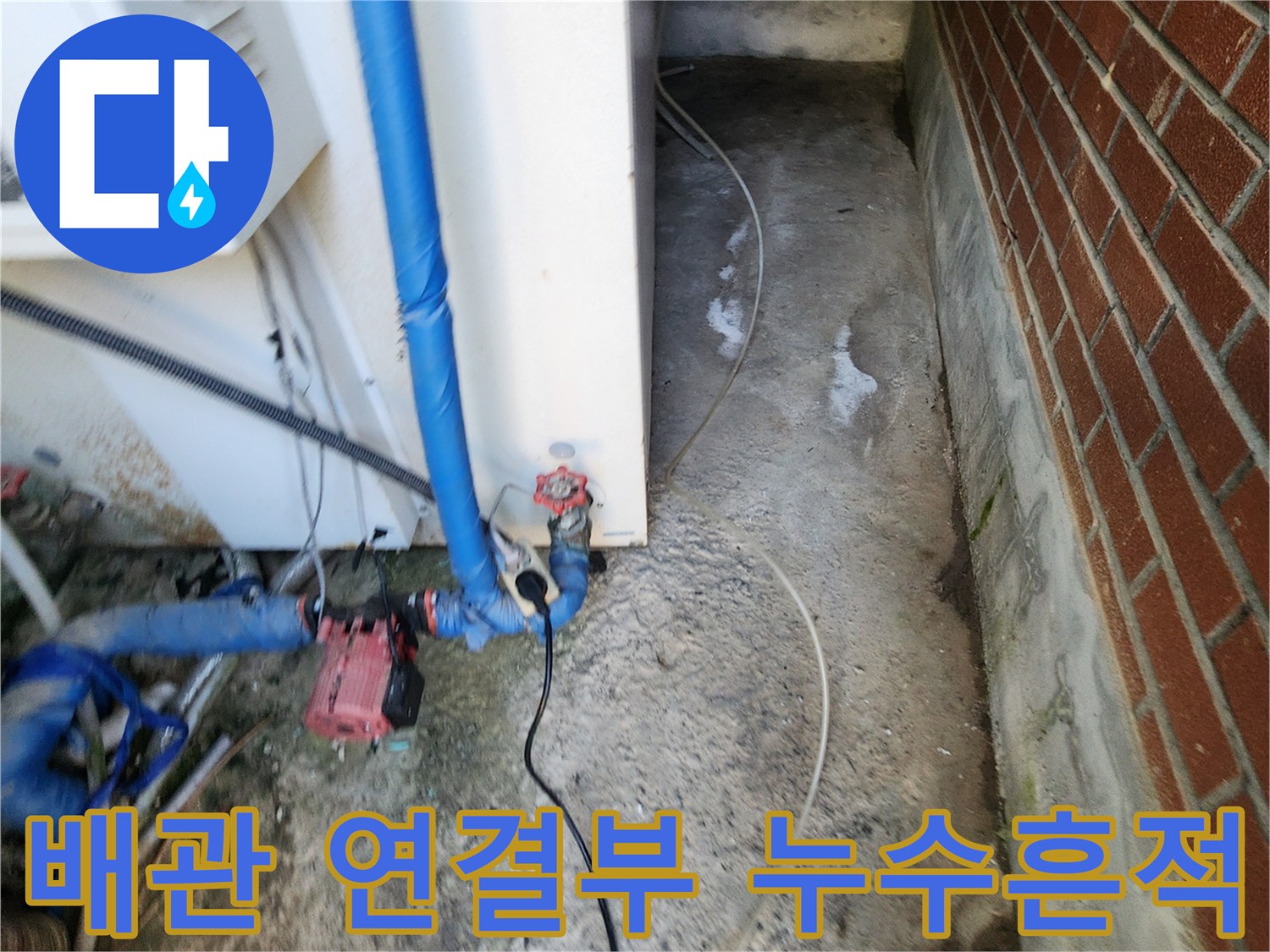 파란색 배관 하단 밸브 주변의 젖은 콘크리트 바닥