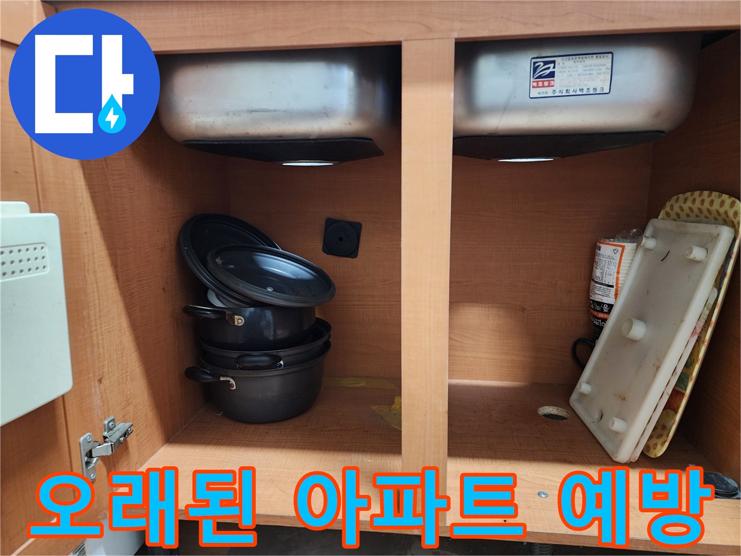 싱크대 하부장 내부 - 누수 지점을 찾기 위해 집중하고 있습니다.