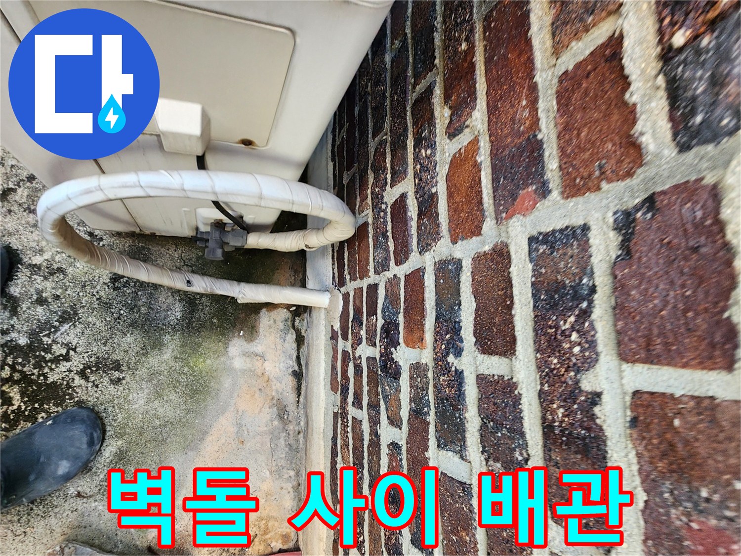 벽돌 벽면 아래쪽으로 지나가는 하얀색 배관 연결 부위