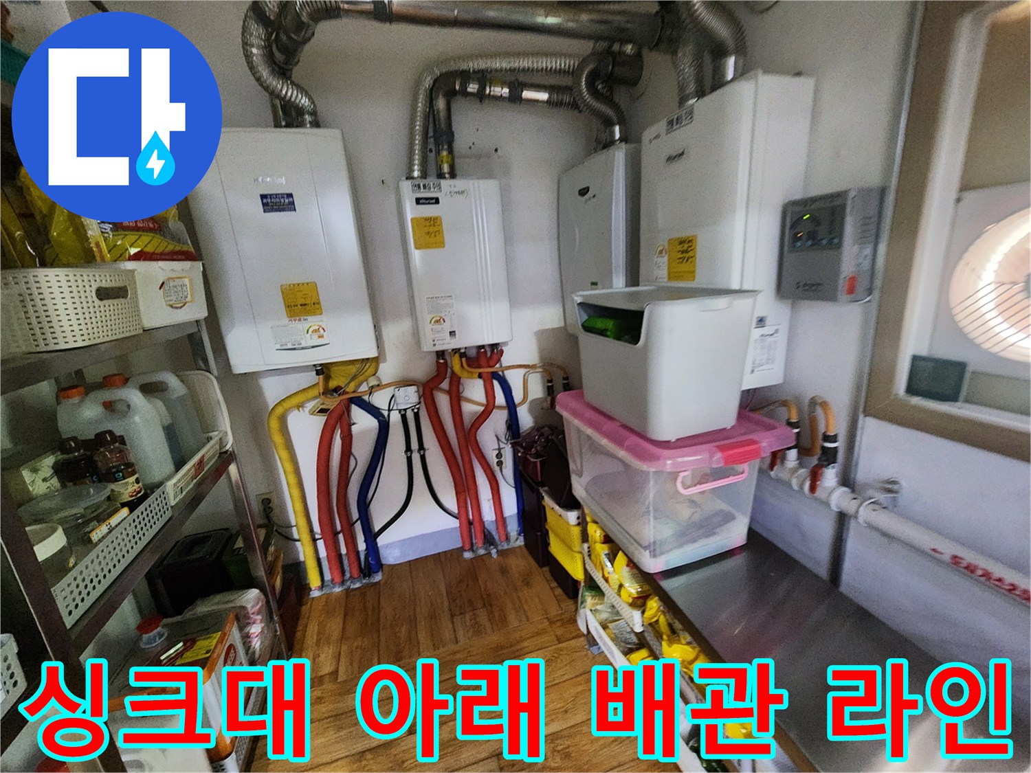 주방 싱크대 하단에 복잡하게 설치된 급수 및 보일러 배관