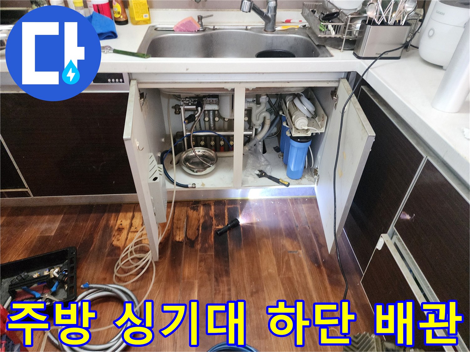싱크대 밑 배관과 젖어있는 바닥재의 근접 사진입니다.