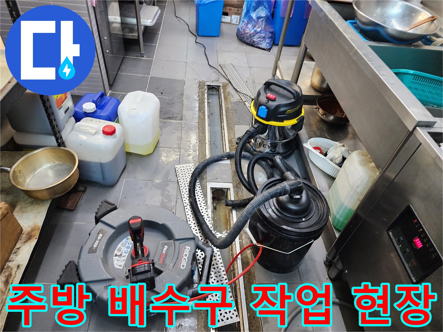 포천 식당 주방의 트렌치 배수구 주변에 놓인 전문 청소 장비와 흡입기