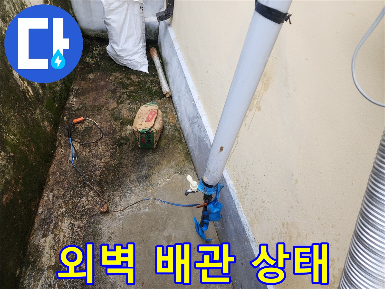 건물 외벽에 연결된 흰색 배관과 파란색 부속의 모습입니다.