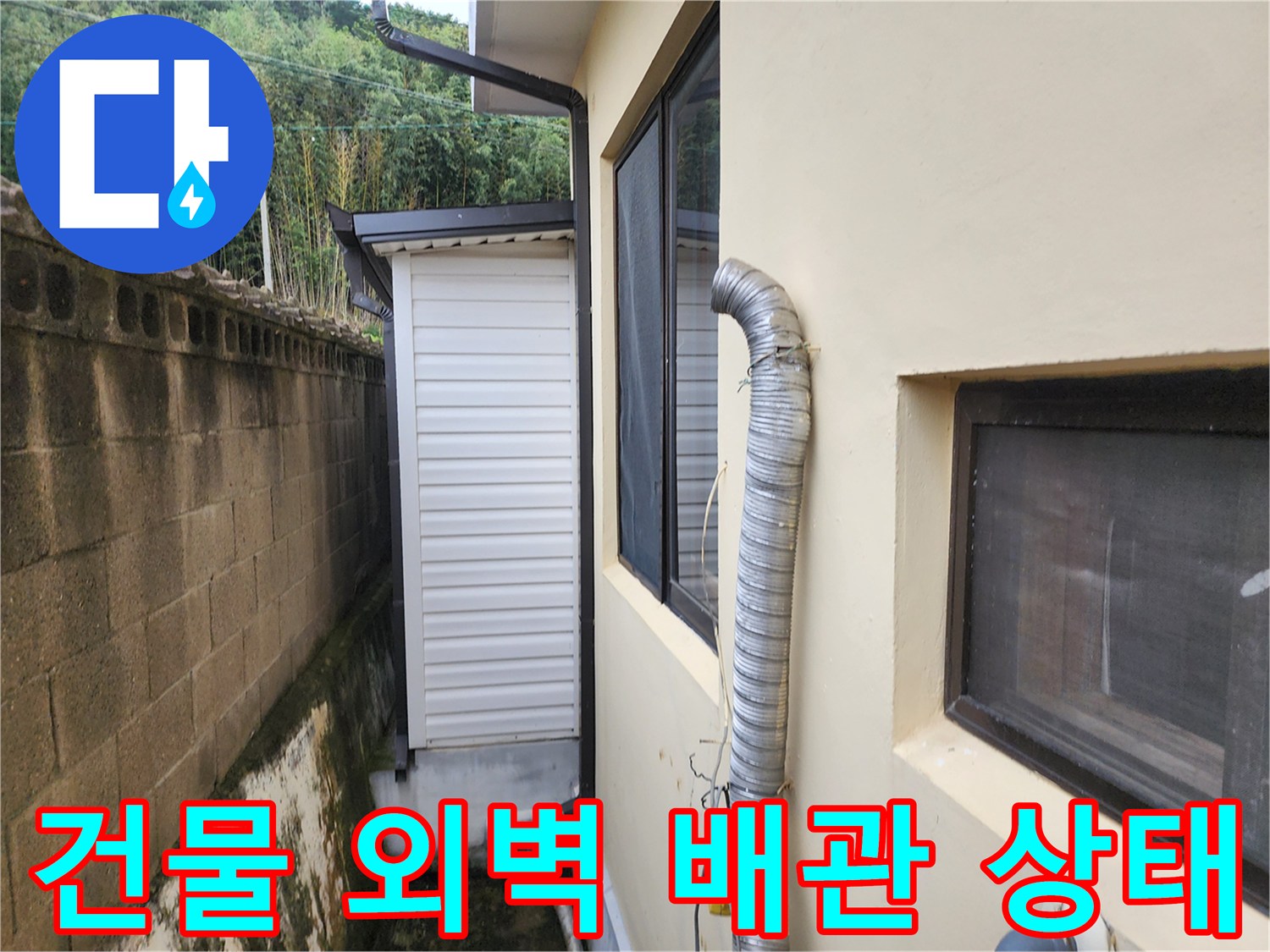 건물 외부 벽면에 설치된 은색 주름관과 창문 주변 모습