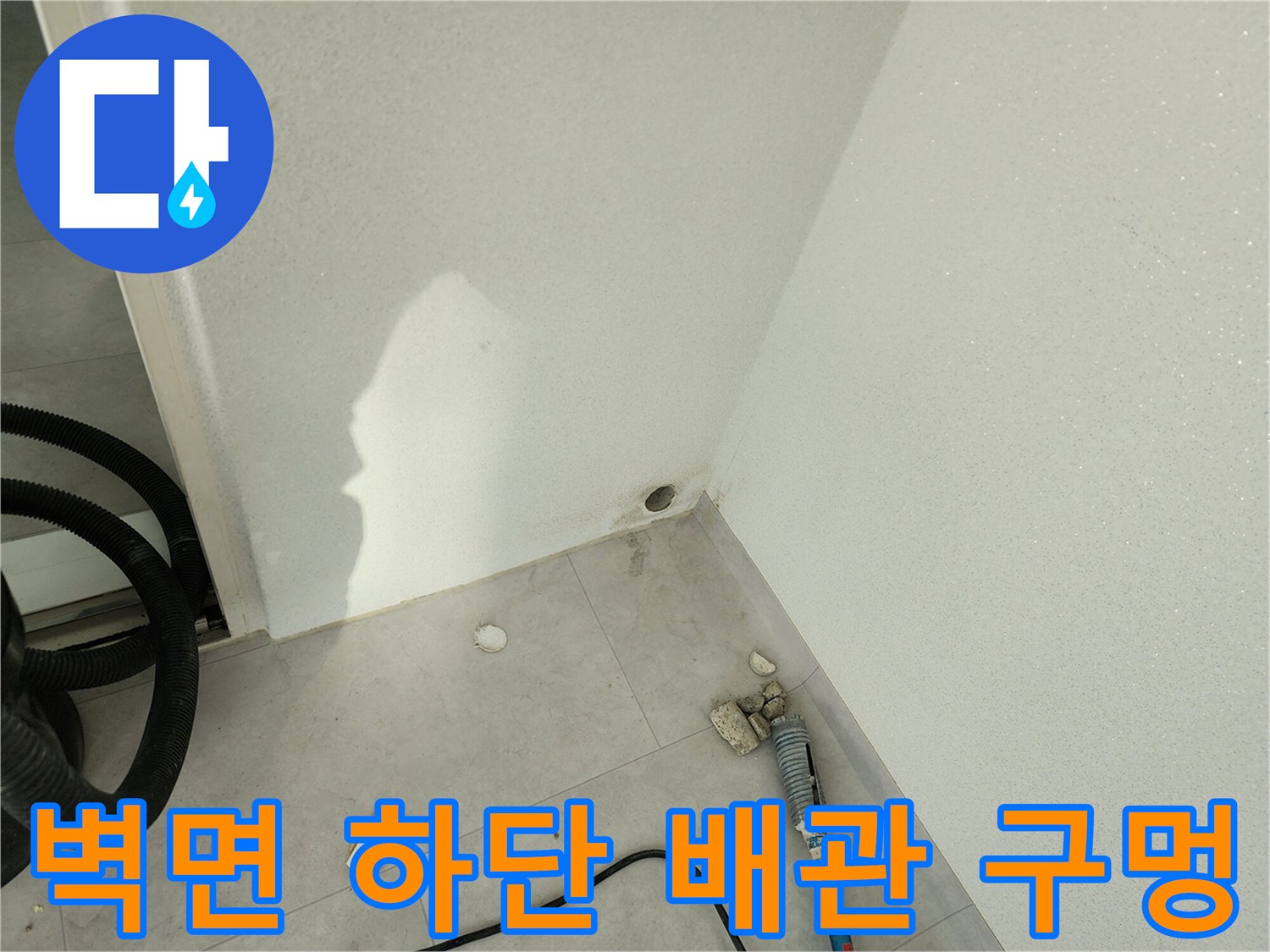 벽면 아래쪽 빈 공간과 주변에 흩어진 타일 조각