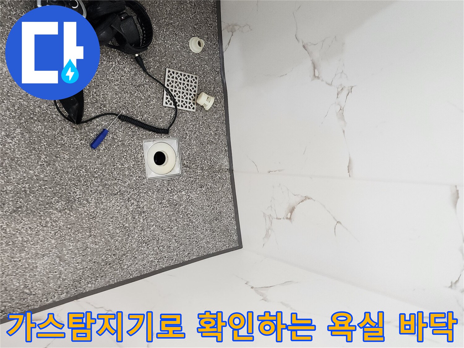 욕실 바닥 배수구 주변에서 가스 탐지기를 사용하여 누수 지점을 찾는 모습