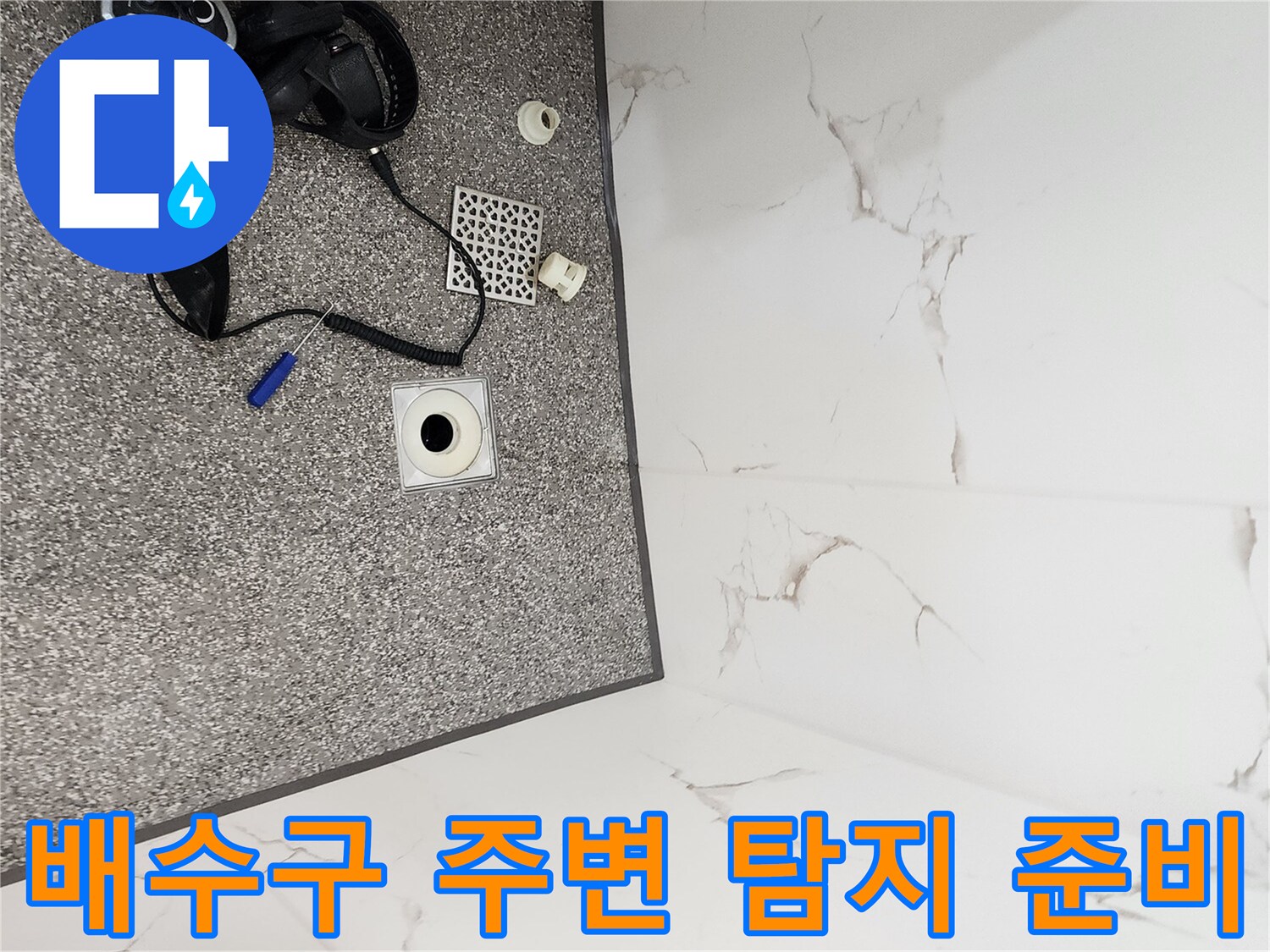 욕실 바닥의 가스 누출 탐지기와 탈거된 배수구 부품들