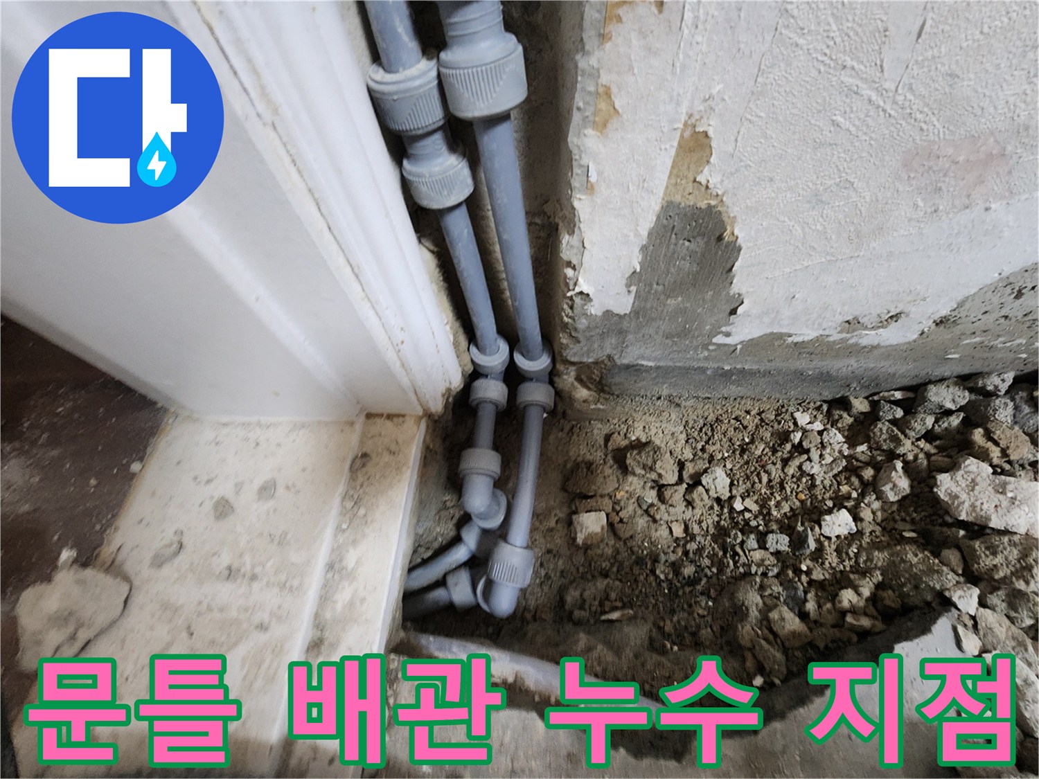 문틀 하단에 노출된 회색 배관 연결 부위의 누수 상태 확인