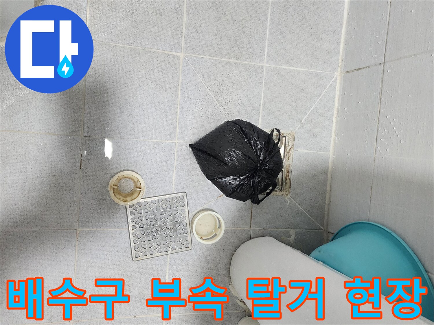 욕실 바닥에 놓인 배수구 구성품과 청소 도구 사진입니다.