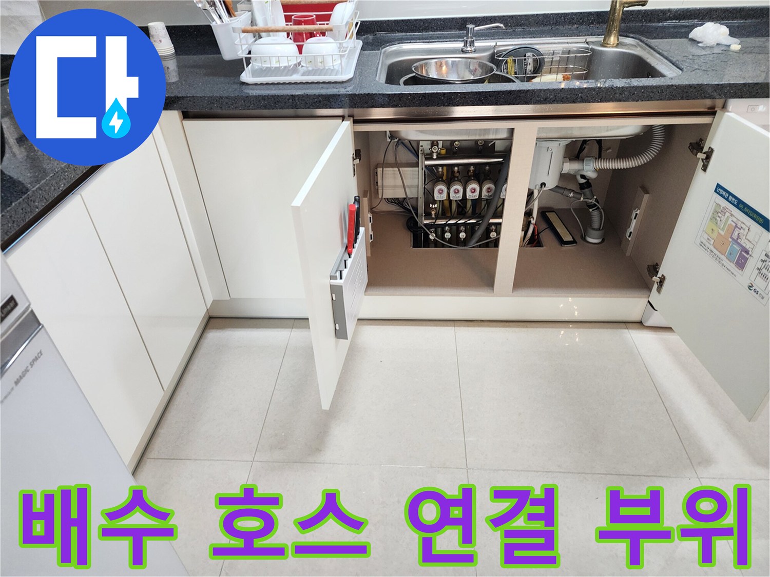 싱크대 하부장 내부-복잡하게 얽힌 배수 호스와 관 연결 상태