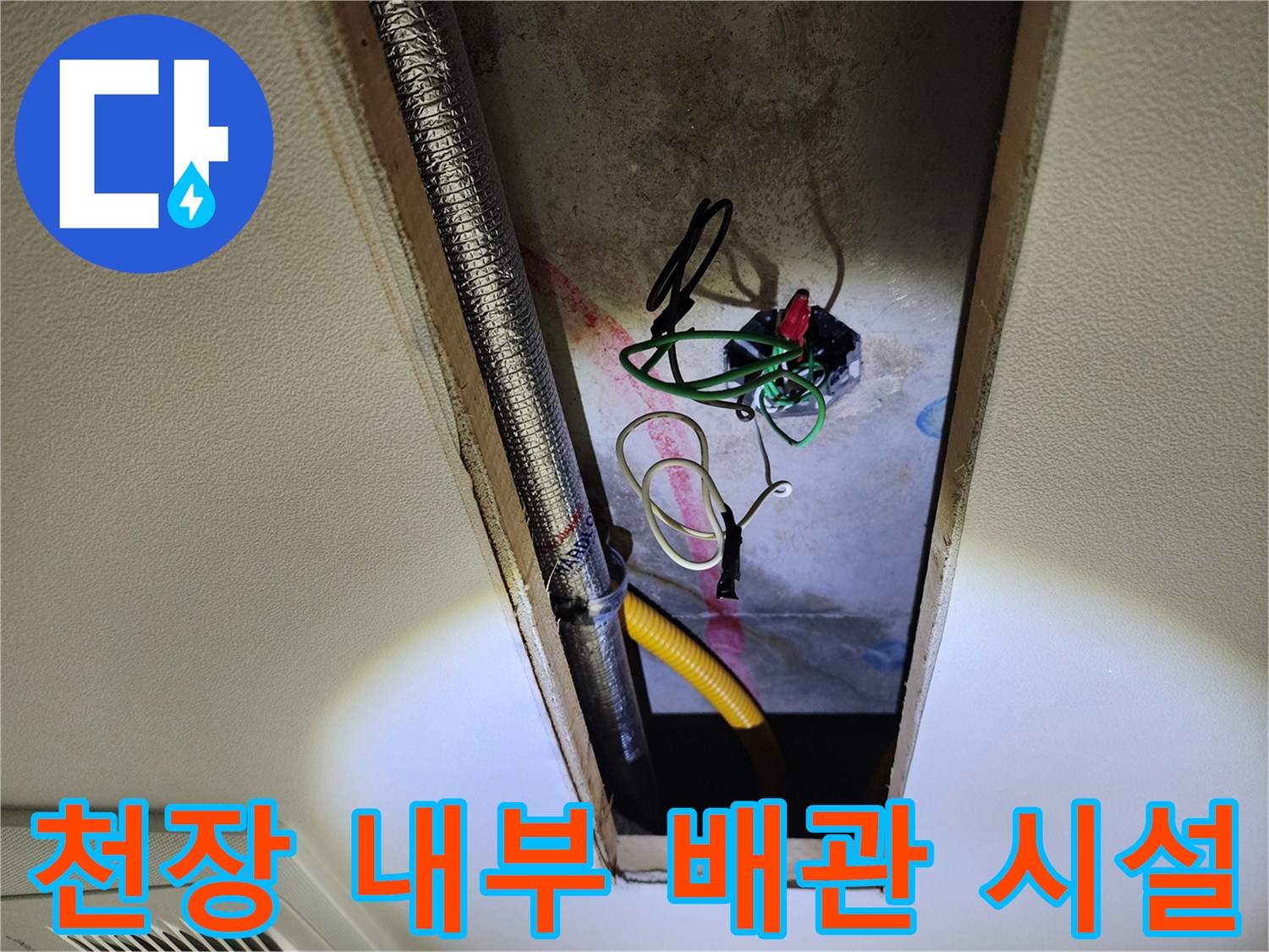 점검구 내부-은색 주름관과 전선이 얽혀 있는 배관 설비 사진