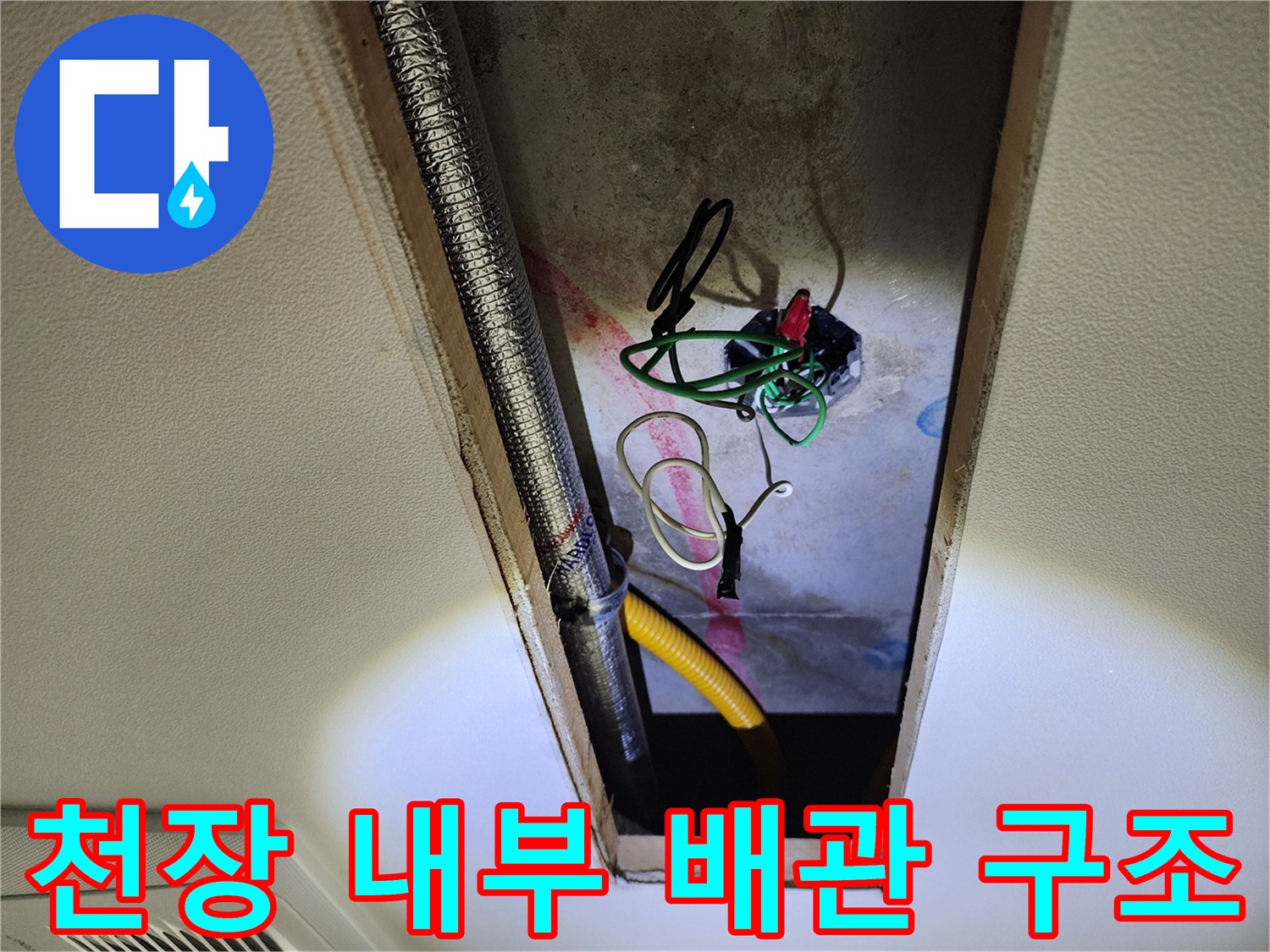 점검구 안쪽의 노란 호스와 은색 관 및 노출된 전기 배선