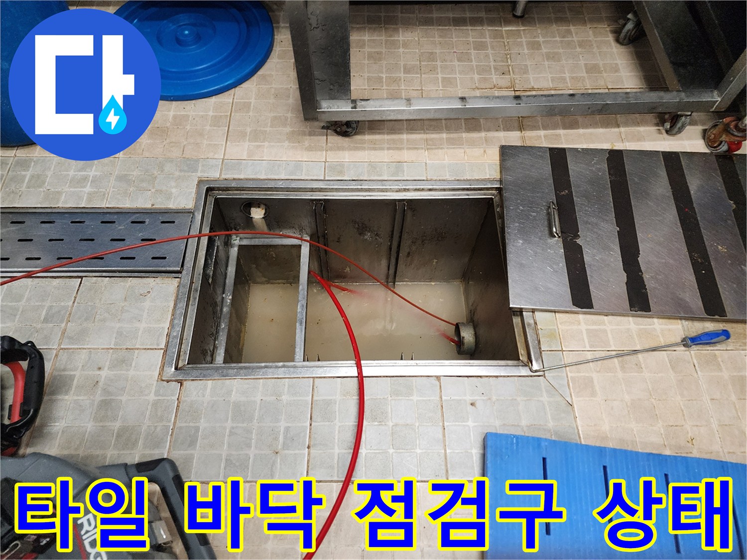 타일로 된 배관 점검구 내부와 노출된 장비 케이블