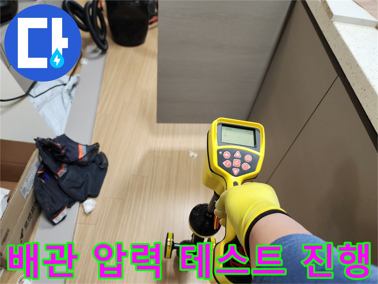 노란 장갑을 낀 작업자가 디지털 게이지로 배관 압력을 측정함