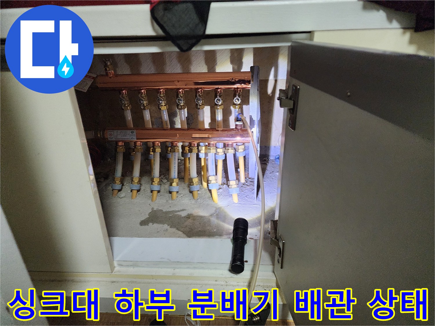 싱크대 아래 설치된 난방 분배기와 연결 배관의 모습