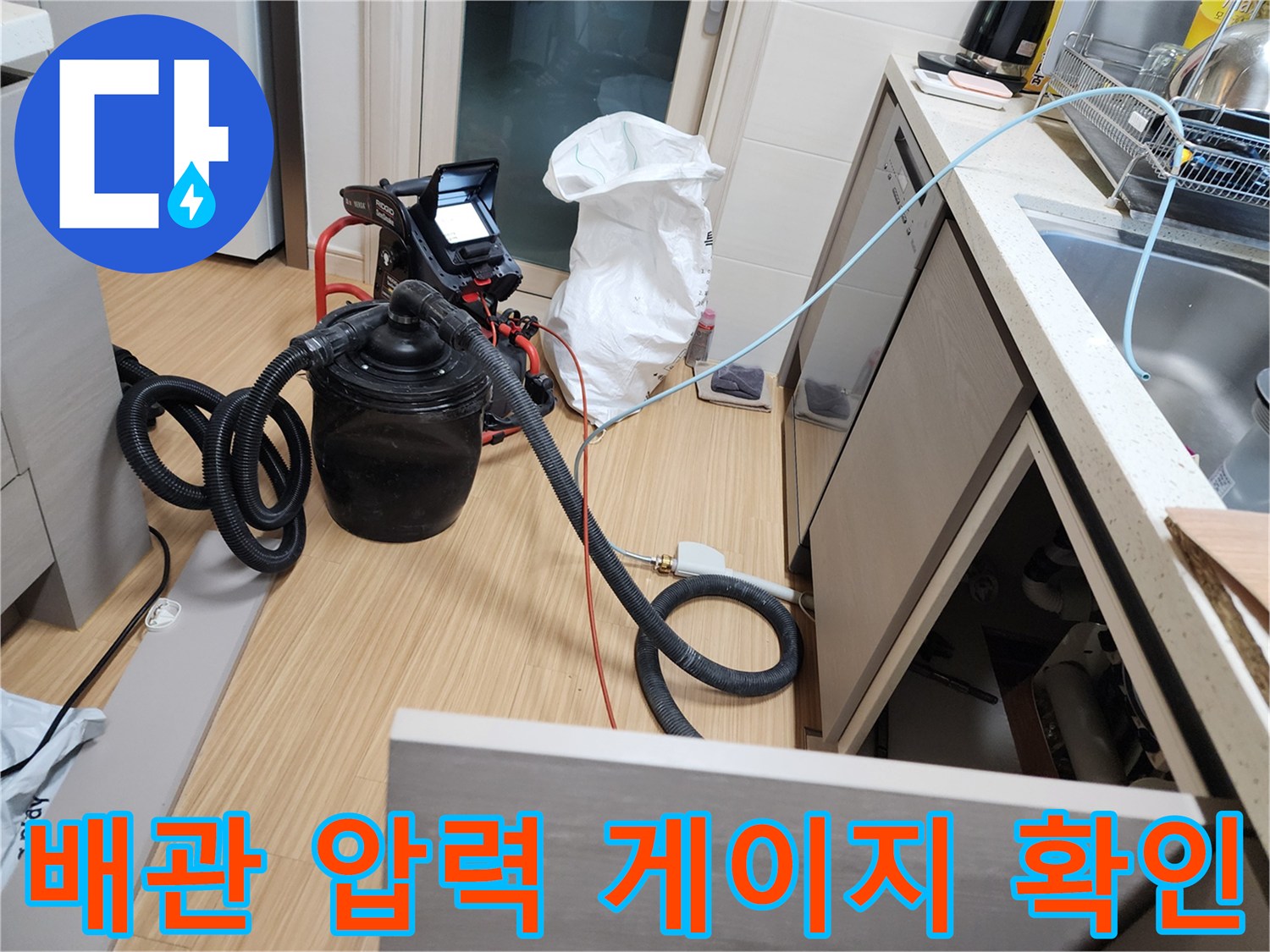 싱크대 하부 배관에 연결된 검은색 공압 테스트 장비