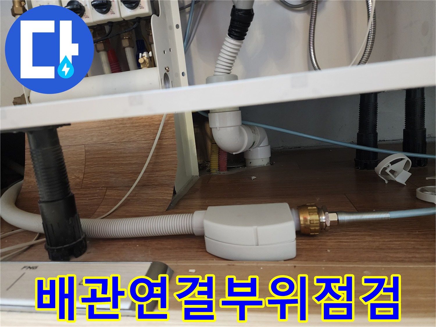 은색 주름관과 흰색 배관이 연결된 싱크대 하단 부속 상세 사진