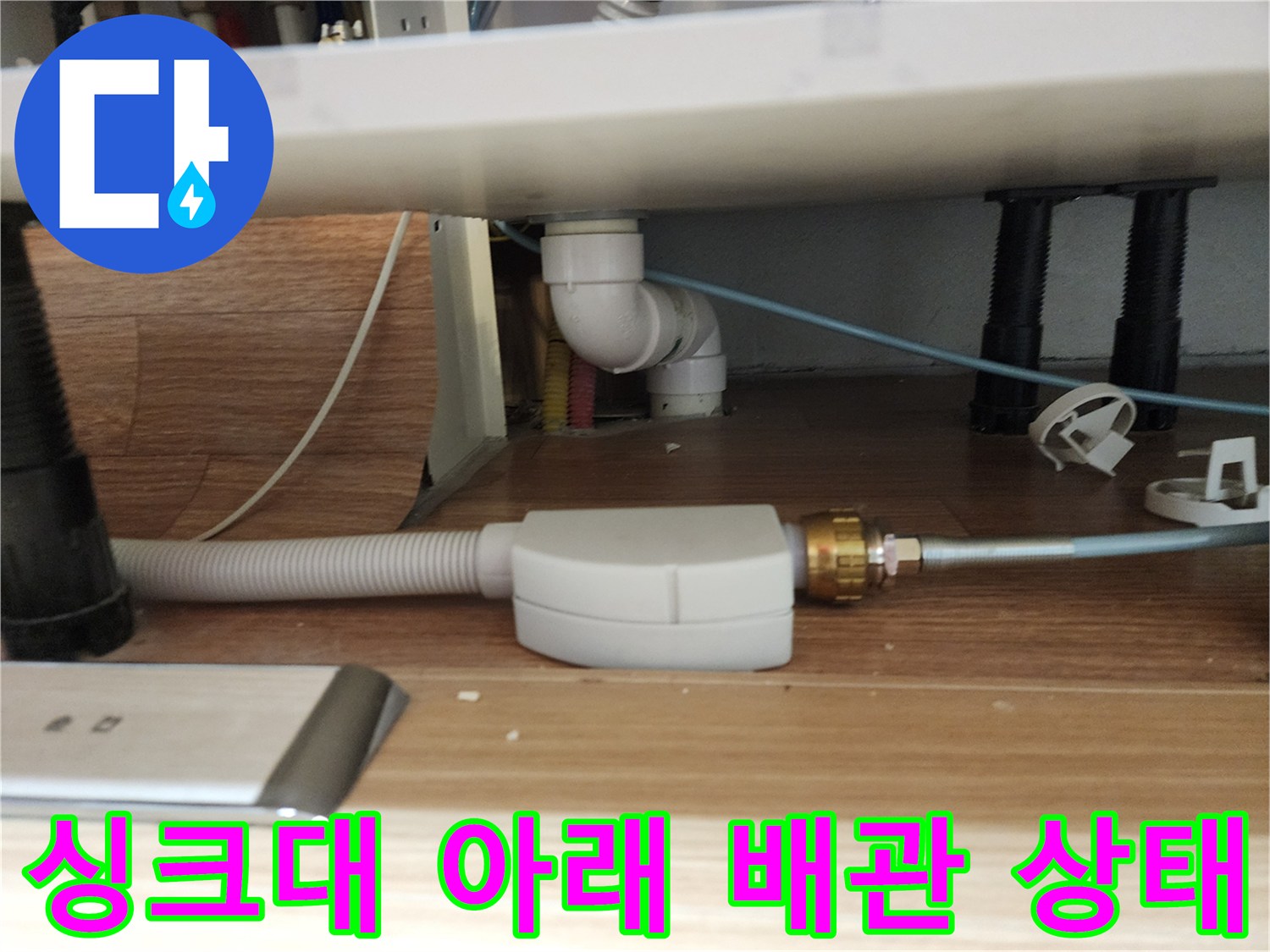 주방 싱크대 밑 하얀색 플라스틱 부속과 회색 호스 연결 모습
